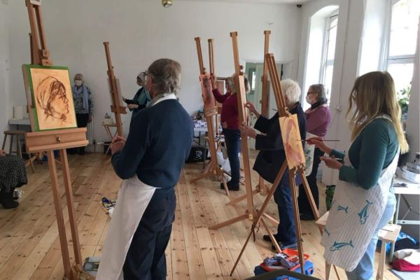 Eine Gruppe malt gemeinsam Bilder auf Staffeleien
