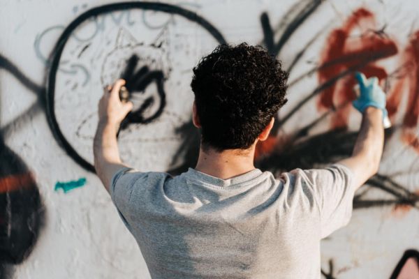 Mann sprüht Graffiti an eine Wand