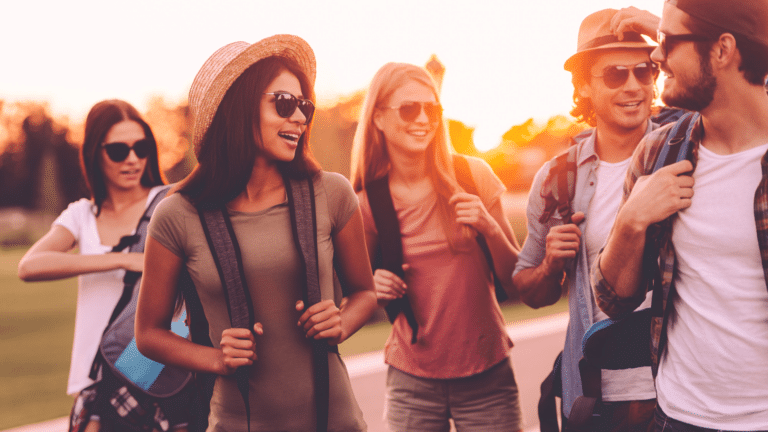 Junge Teamgruppe bei einem Teambuilding in Bayrischzell, lachend und mit Rucksäcken unterwegs in der Natur bei Sonnenuntergang