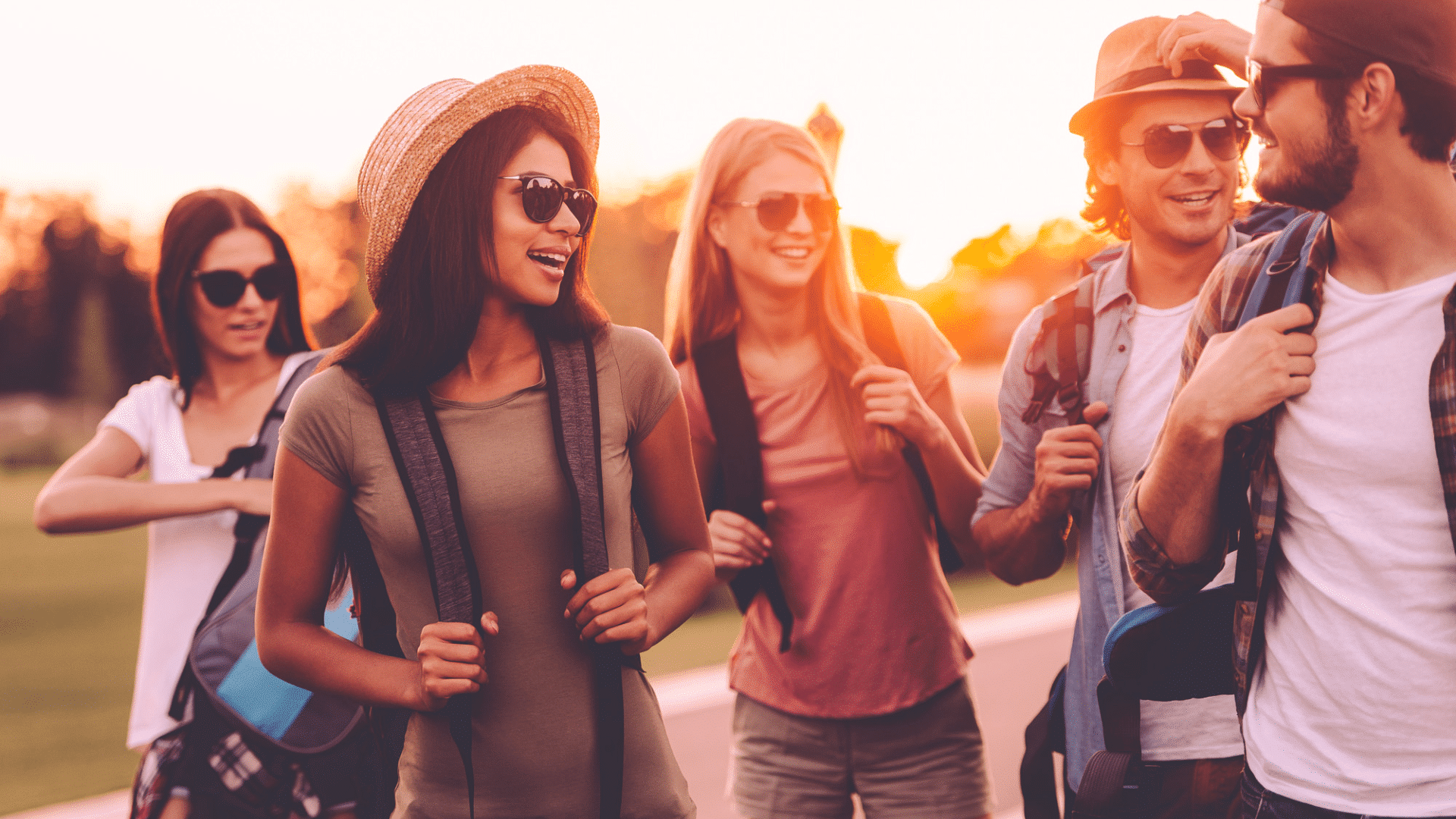Junge Teamgruppe bei einem Teambuilding in Bayrischzell, lachend und mit Rucksäcken unterwegs in der Natur bei Sonnenuntergang