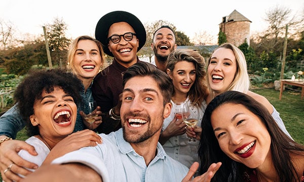 Fröhliche Gruppe junger Menschen bei einem Teambuilding in Bayrischzell – gemeinsamer Moment mit Drinks und guter Stimmung im Grünen