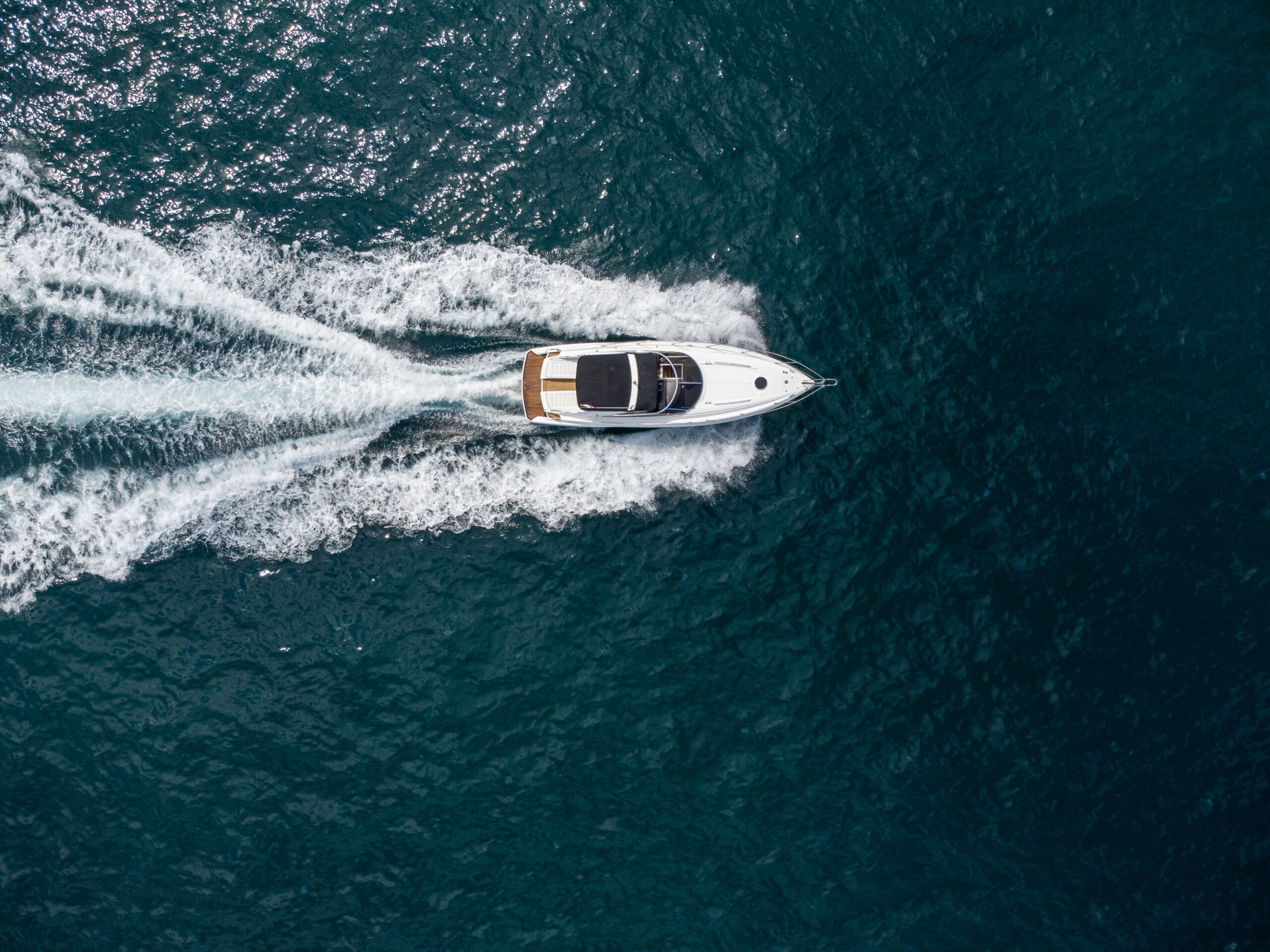 Motorboot aus der Vogelperspektive fährt über tiefblaues Meer